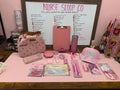 Pink and sparkly healthcare gift box by Nurse Scoop Co with lunch tote, glitter tumbler, clipboard, hat, compression socks, pens, badge accessories, and self-care items